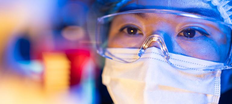 Closeup of female scientist wearing a mask and eye protection
