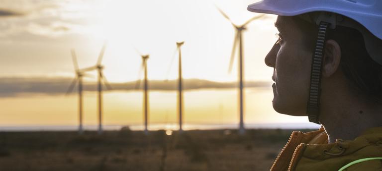 Electricity Maintenance Engineer working on the field at a Wind Turbine Power station at sunrise