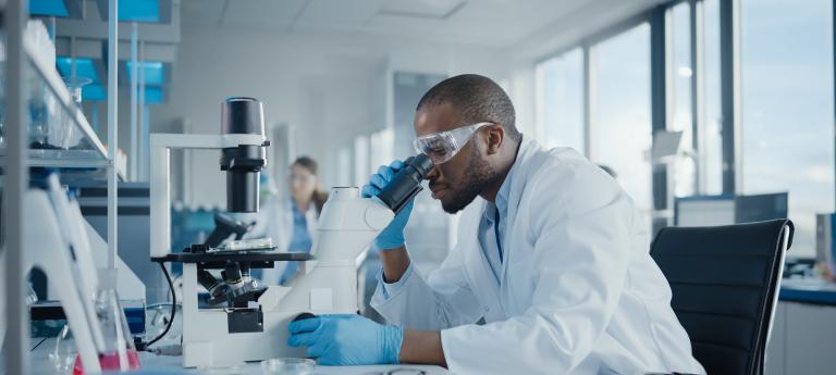 Portrait of Black Male Scientist Looking Under Microscope, Analyzing Petri Dish Sample