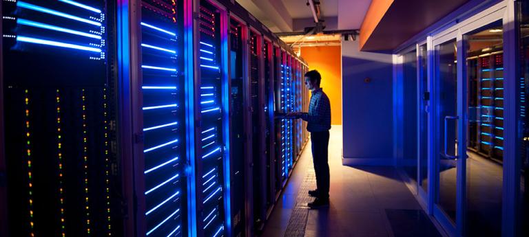 A student inside of a computer room surrounded by hardware