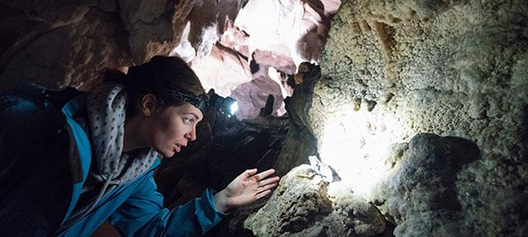 A Case Western Reserve University student wearing a headlamp in a cave