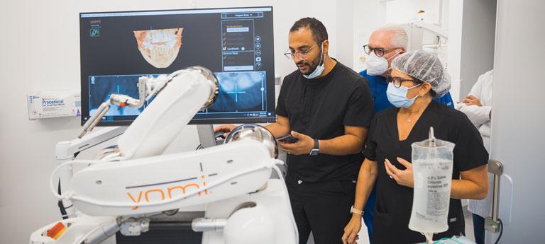 Case Western Reserve University dental faculty and students looking at a computer screen with x-rays near yomi robot