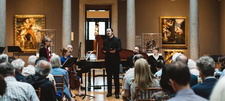 A CWRU student sings in front of an audience at Cleveland Museum of Art