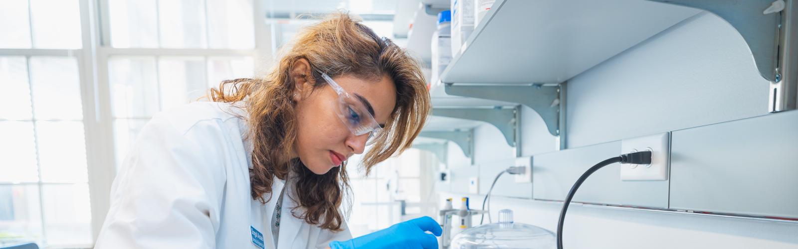 Side view of a 3.1.7 School of Biomolecular Engineering student measuring liquids with lab equipment