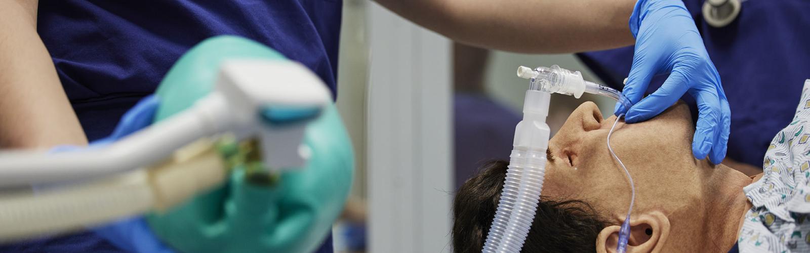 An anesthesiology student practicing on a medical mannequin.