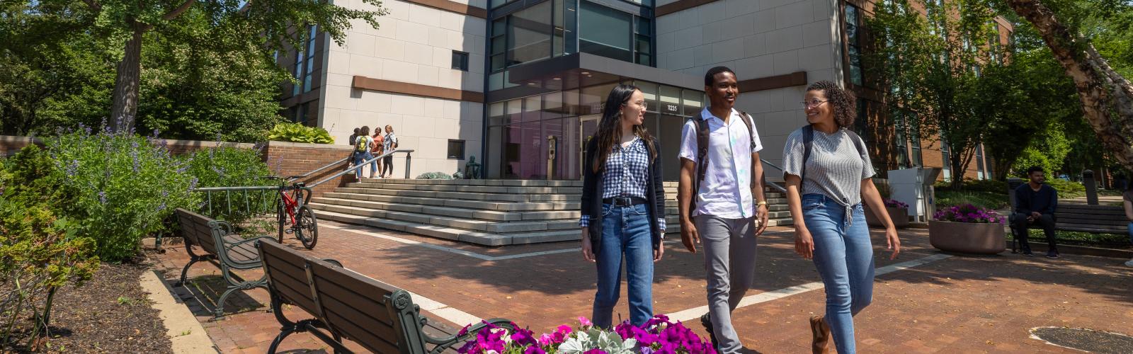 Three Mandel students walk outside a building on campus