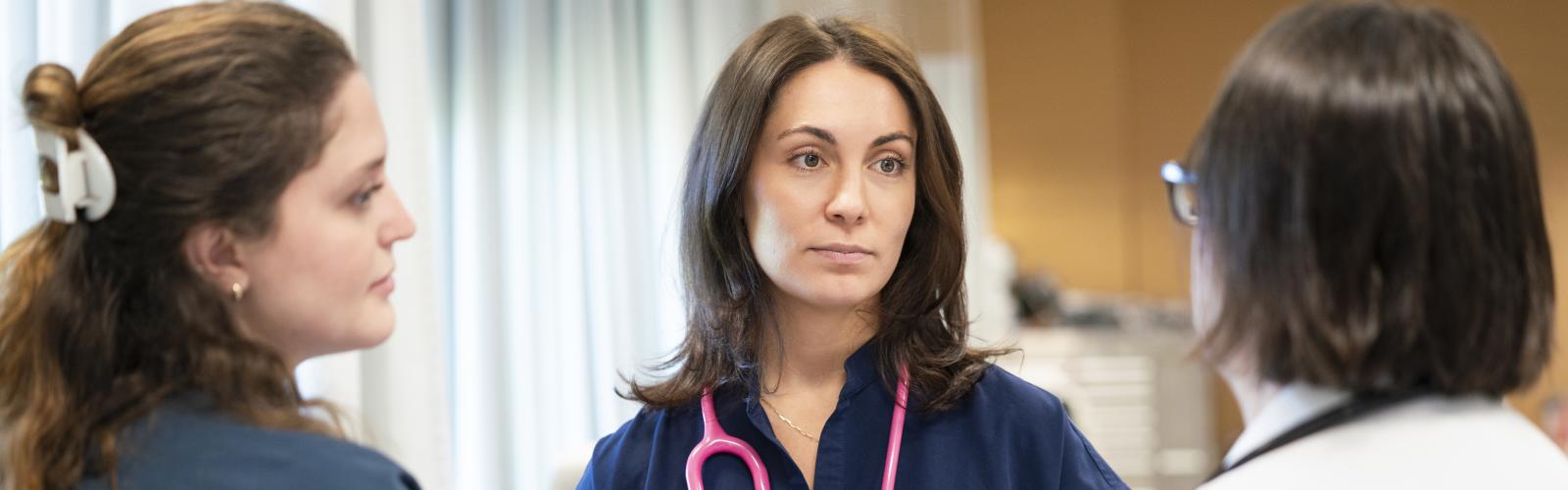 Two nursing students talking with a professor