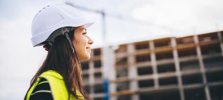 An engineering in a hard hat standing in front of a building