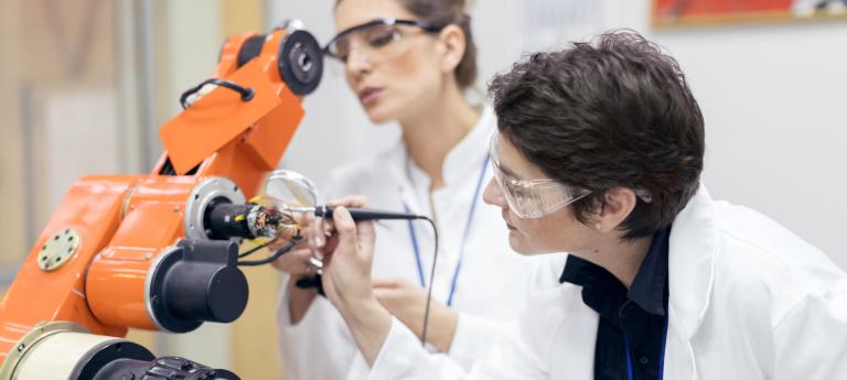 Female engineers repairing electronic machine in research lab