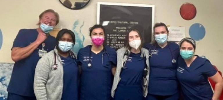 Six students of various genders and ethnicities pose in scrubs behind a table with medical gear
