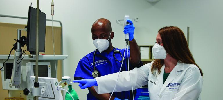 A student and instructor engaged in anesthesiology lab.