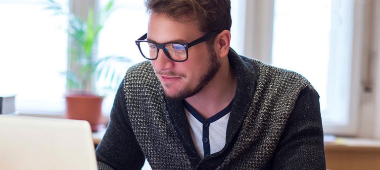student with glasses looking at computer