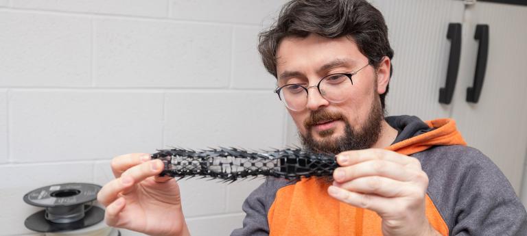Mechanical engineering student holding a piece of a robot