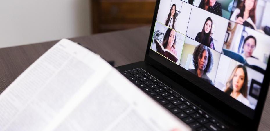 A group of people on a computer screen next to an open book