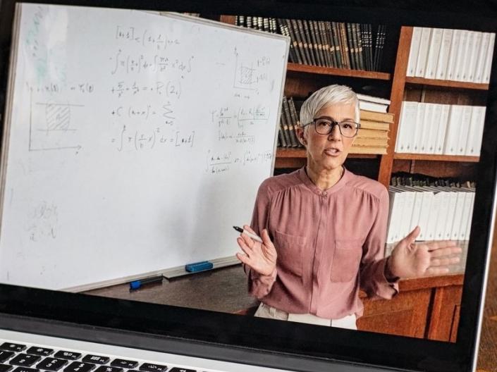 An instructor, seen on a laptop, teaching a course remotely,