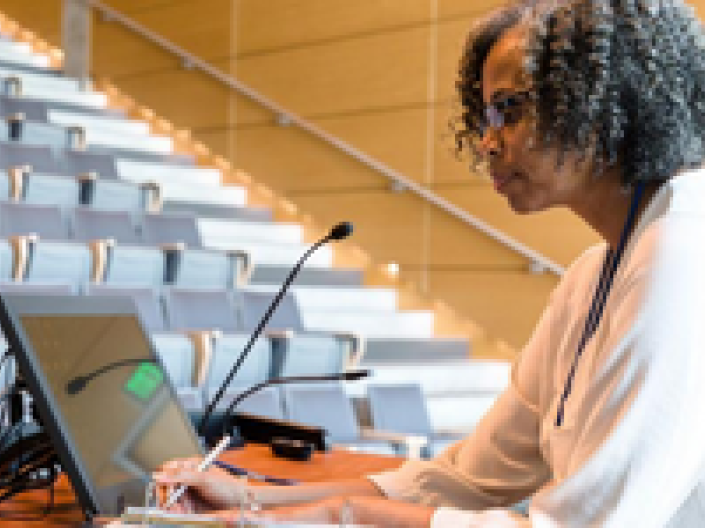 A woman looking at a computer screen preparing to teach a class.