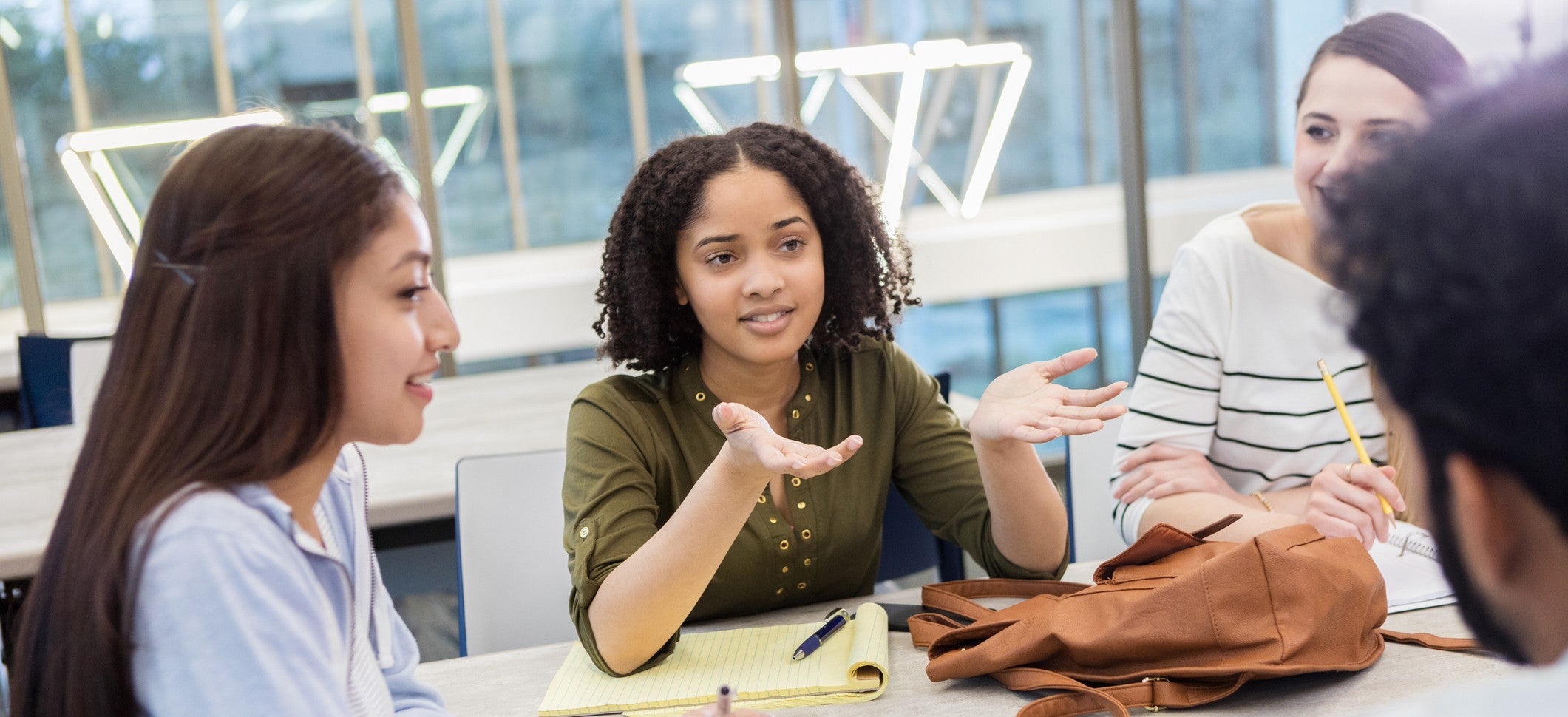 Female college student gestures while talking with study group