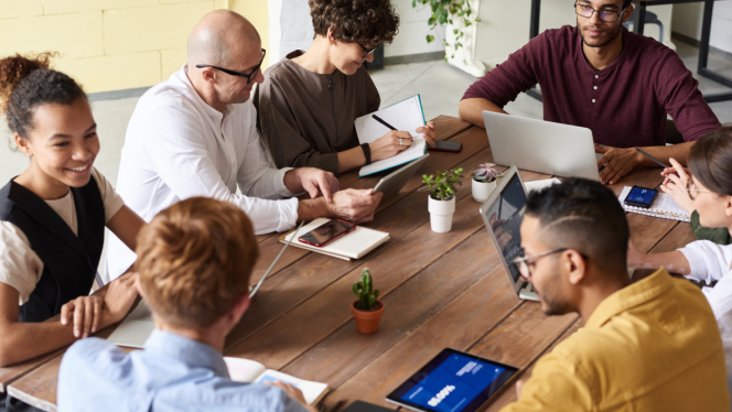 Group of people planning around the table with paper and computers