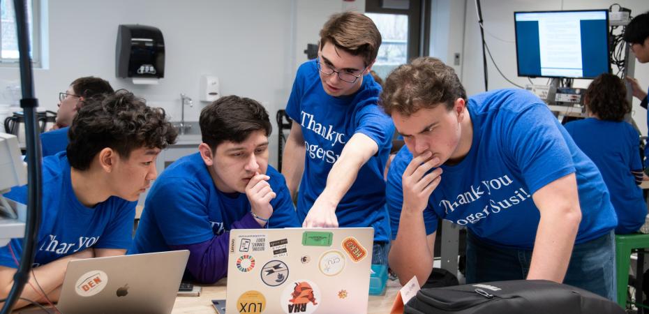 A group of students looking at a laptop.