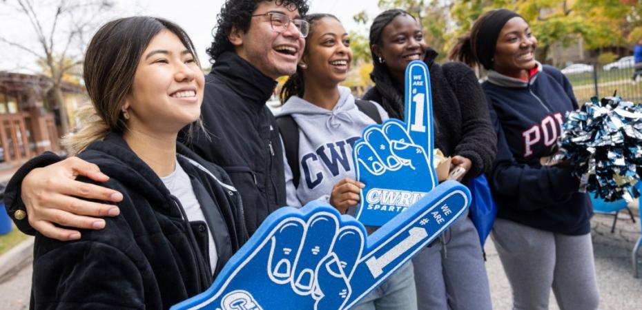 A group of students smiling and holding a foam finger.