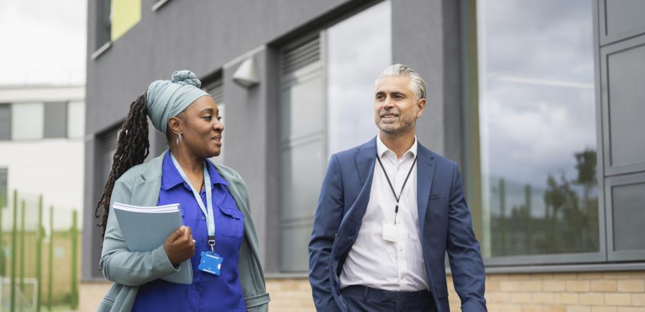 Male and female school administrators walking on campus 