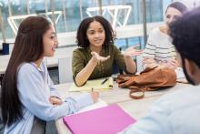 Female college student gestures while talking with study group