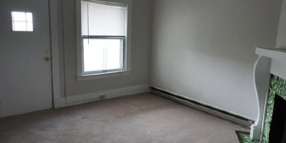White bedroom with beige carpet, fireplace and large bright window