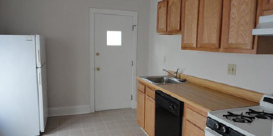 White kitchen with wooden cabinets, stove and refrigerator