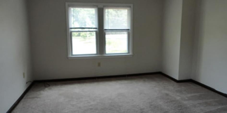 White carpeted living room with four bright windows 