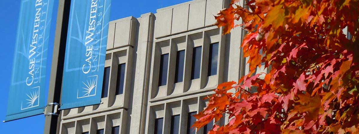 Crawford Hall with CWRU flag and tree with red leaves.