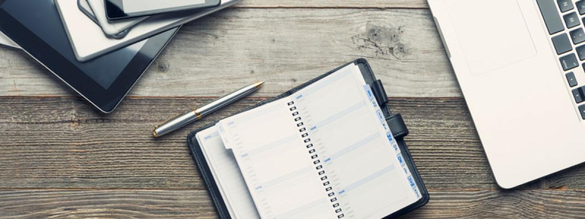 Tablets and phones, a pen and planner, and part of a laptop.