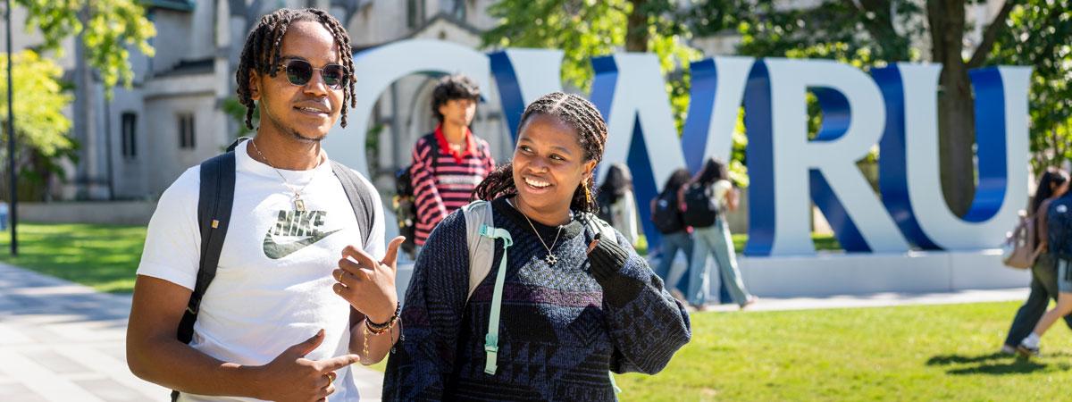 Two Case Western Reserve University students walking in front of the CWRU letters on the binary walkway