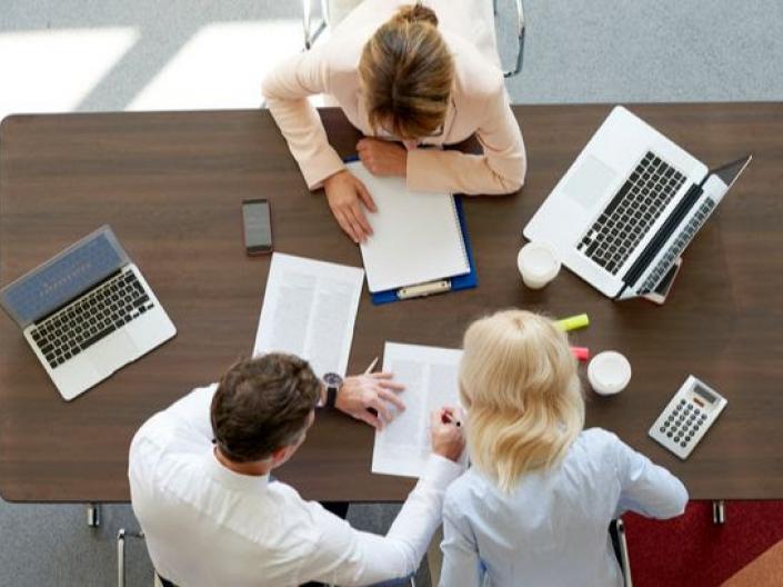 A team working together at a desk with papers and computers