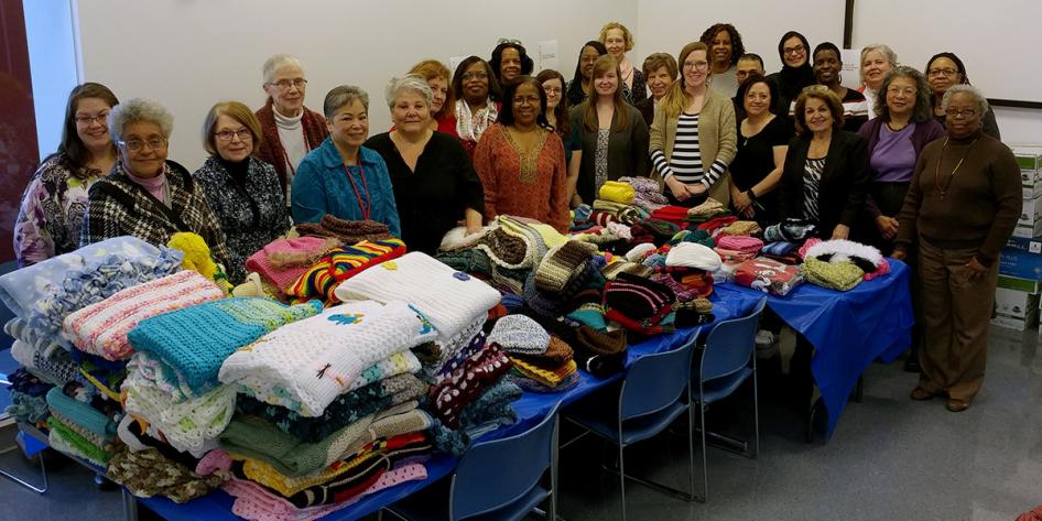 The Crafters at Case group in 2018 with knitted items on a table.