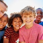 Photograph of children from various racial and ethnic backgrounds smiling at the camera