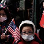 Photograph of young Asian children holding American and Chinese flags, and wearing face masks