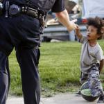 Photo of a small child and a police officer reaching out to him