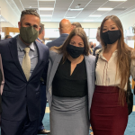 Photograph of five individuals standing arm in arm in a New Orleans office building wearing face masks