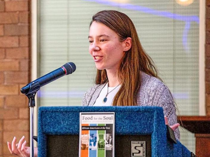 Photo of student standing at a podium giving a talk