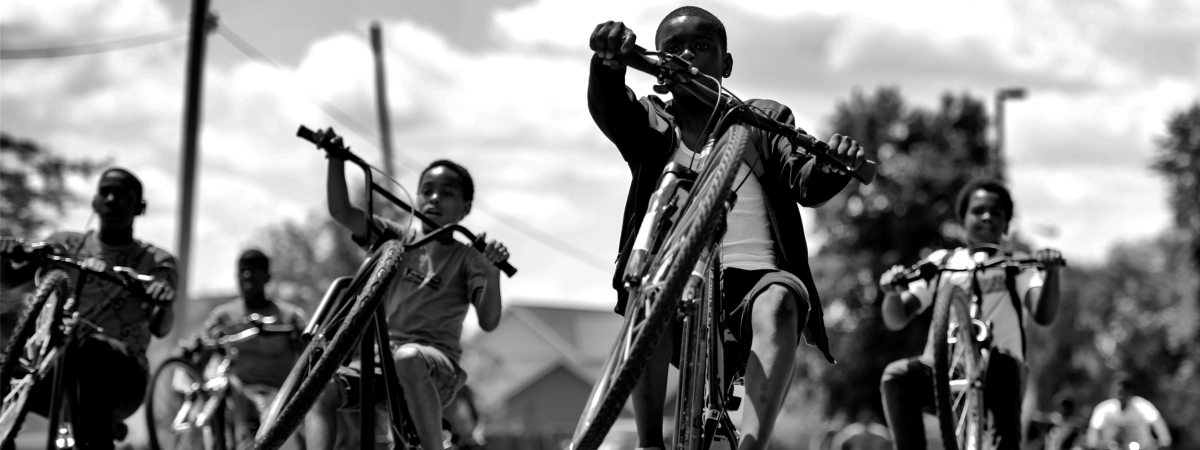 Photo of young Black boys on bicycles popping wheelies
