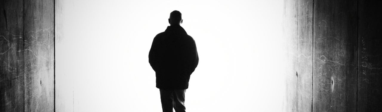 dark silhouette of a man walking towards a bright light