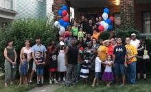 Large group of diverse people standing in front of house