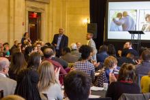Mark Joseph presenting to large group, young man standing up speaking.
