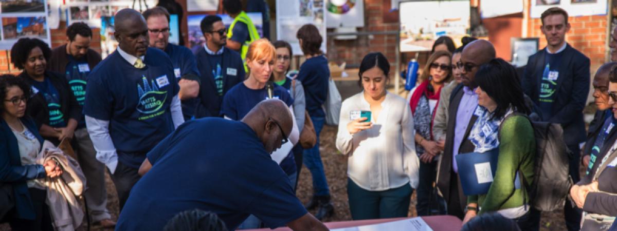 Man moving objects on large map, people around him watching.