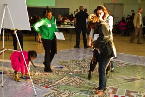 group of people standing on a large map looking down at it