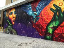 Wall mural of Black woman in front of fireworks, a hawk in flight, and a hand