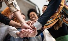 group of people in clircle with hands in middle