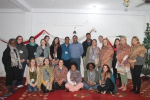 Image of 21 MSASS students in room with red carpet during study abroad trip