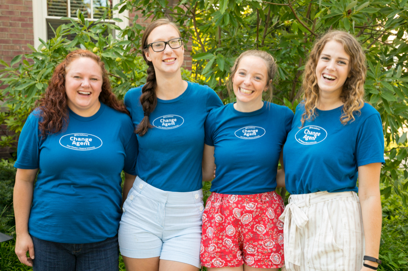 4 women wearing change agent shirts standing with arms around each other