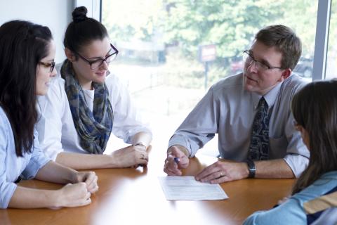 Faculty sitting and talking with three students at table